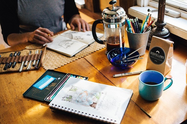 man sitting at table drawing commissioned artwork