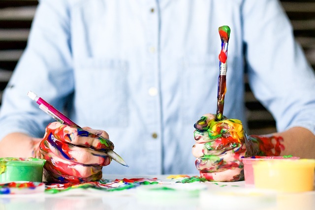 person holding paint brushes covered in paint