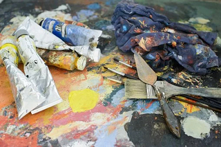 paints, palette knives and brushes in a messy studio